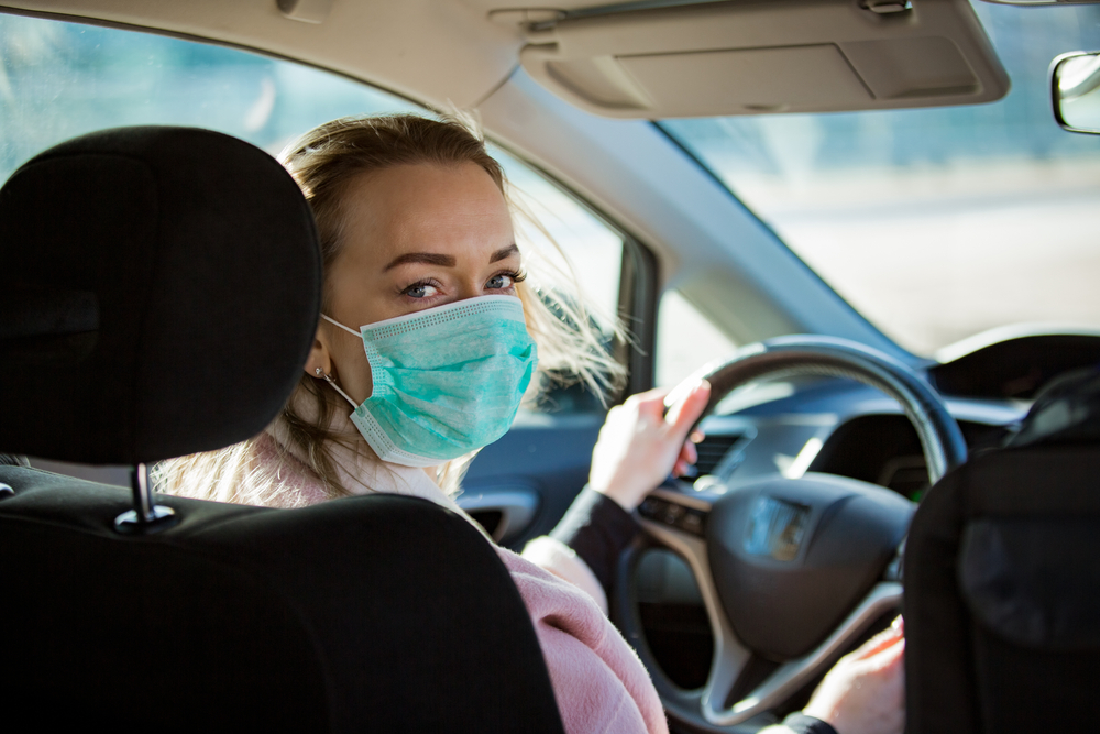 A woman wears a mask while driving